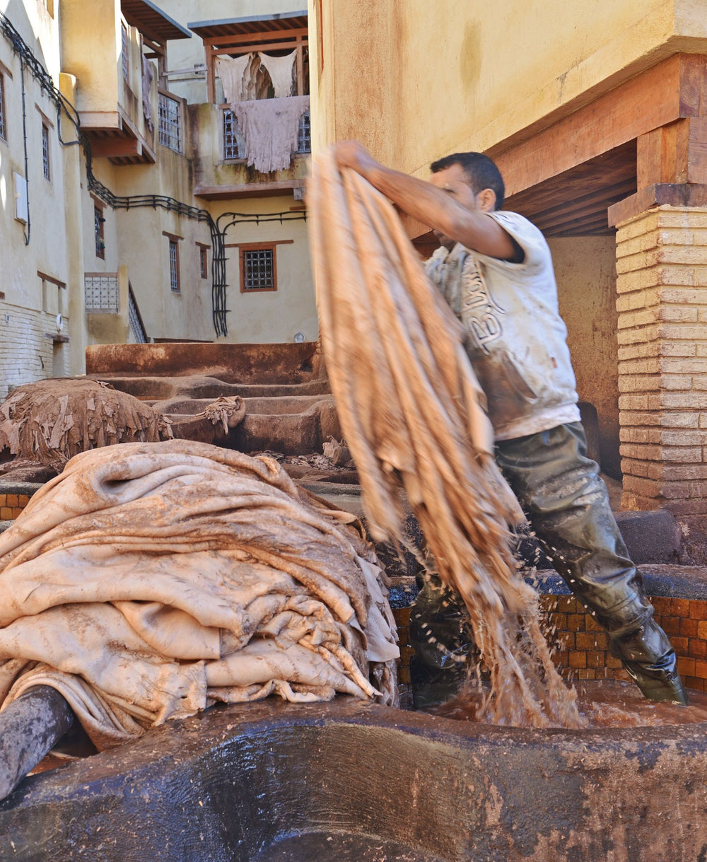 Traditional artisan handling hides during leather processing at a Moroccan tannery
