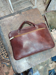 MARZAVEL brown leather document briefcase resting on workshop table, handles and zipper detail