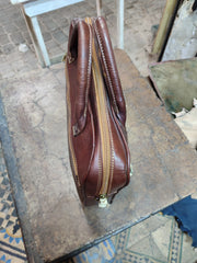 Brown rectangular leather briefcase from side, showing narrow profile and zipper construction