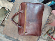 Brown leather document bag viewed from above, top zipper closure and twin padded handles