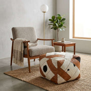 Moroccan brown leather and cowhide-look square pouf beside a lounge chair
