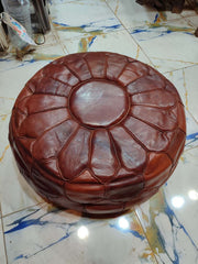 Dark brown round Moroccan leather pouf with petal-shaped stitched panels viewed from above