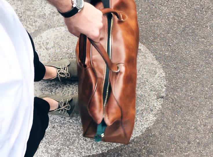 MARZAVEL cognac leather travel bag carried outdoors