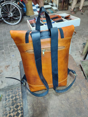 Rear view of cognac leather backpack, two dark shoulder straps and exterior zip pocket