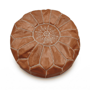 Tan Moroccan round leather pouf with cream medallion embroidery against white