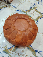Tan round Moroccan leather pouf with flower-petal panel seams photographed from above