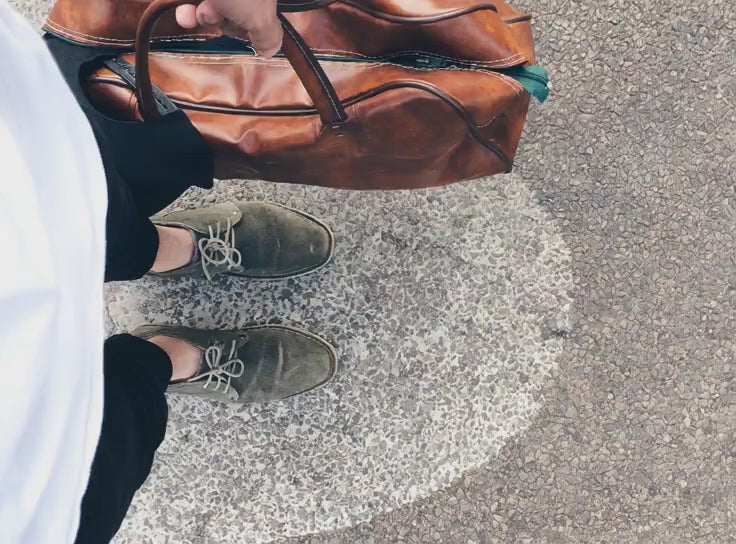 MARZAVEL cognac leather travel bag carried outdoors